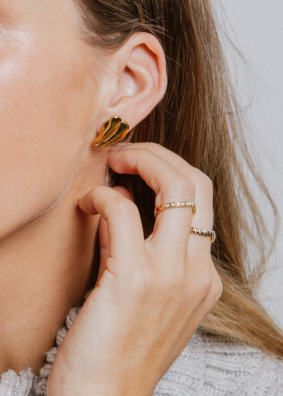 Eternity ring on model, with hand held up to ear, wearing an earring and gold ring.